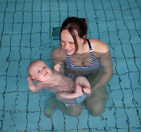 En ung mamma och hennes bebis njuter i vattnet. 