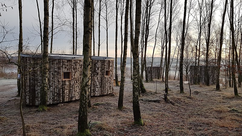 Tre runda vindskydd på lägerplatsen en vinterdag med frost på träden.