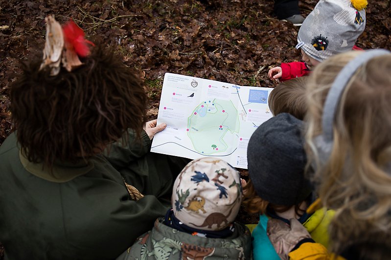 Skogsmulle visar sin karta för flera barn ute i skogen